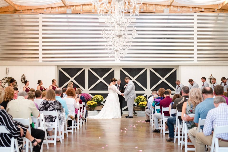 Sillas blancas dispuestas bajo la lámpara de araña dentro del Grand White Barn para una boda de servicio completo cerca de Knoxville