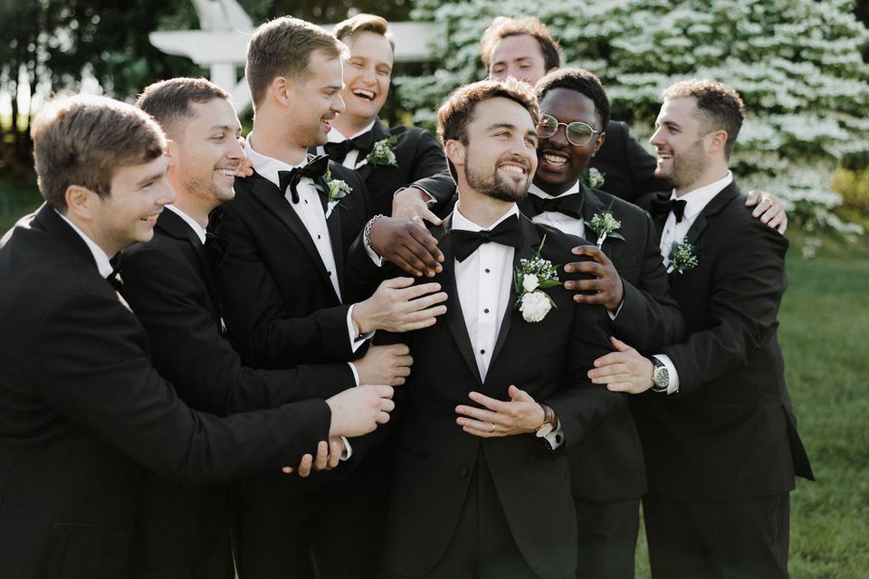 Padrinos riendo juntos junto al arco de ceremonia del estanque en una boda íntima en granja en New Market, Tennessee